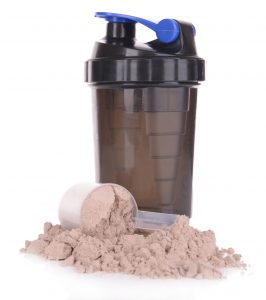 Whey protein powder in scoop and plastic shaker isolated on white